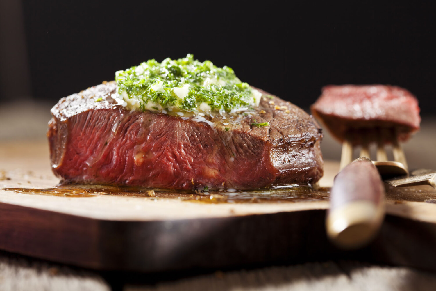 Steak with green butter on wooden board