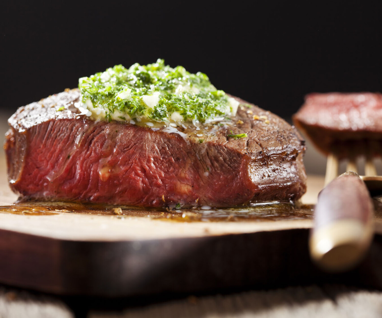 Steak with green butter on wooden board
