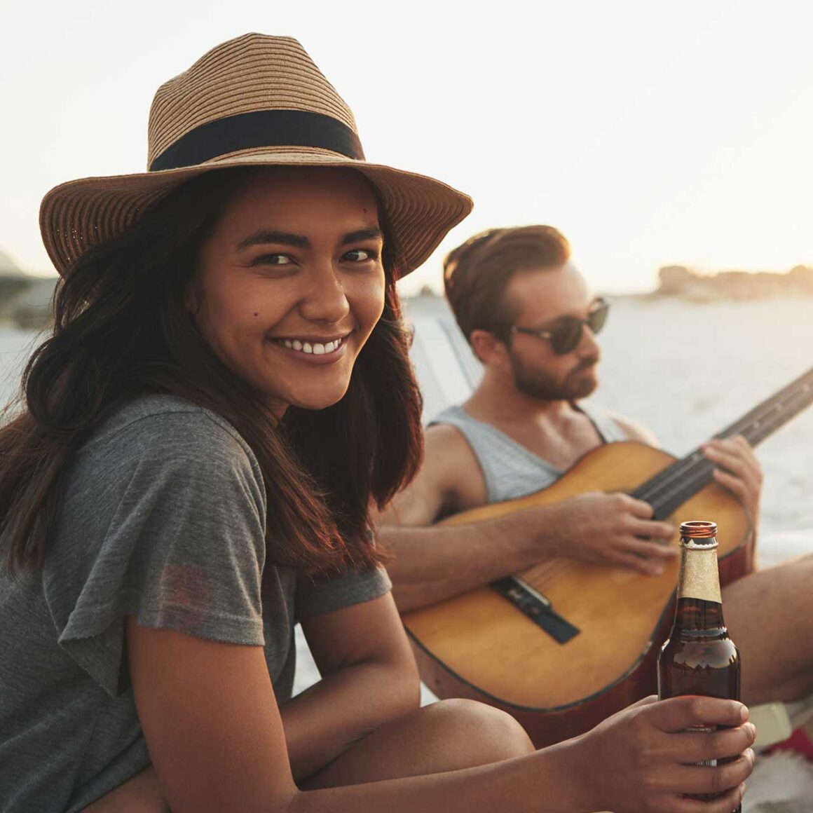 Friends spending time together at the beach with a guitar and a drinks