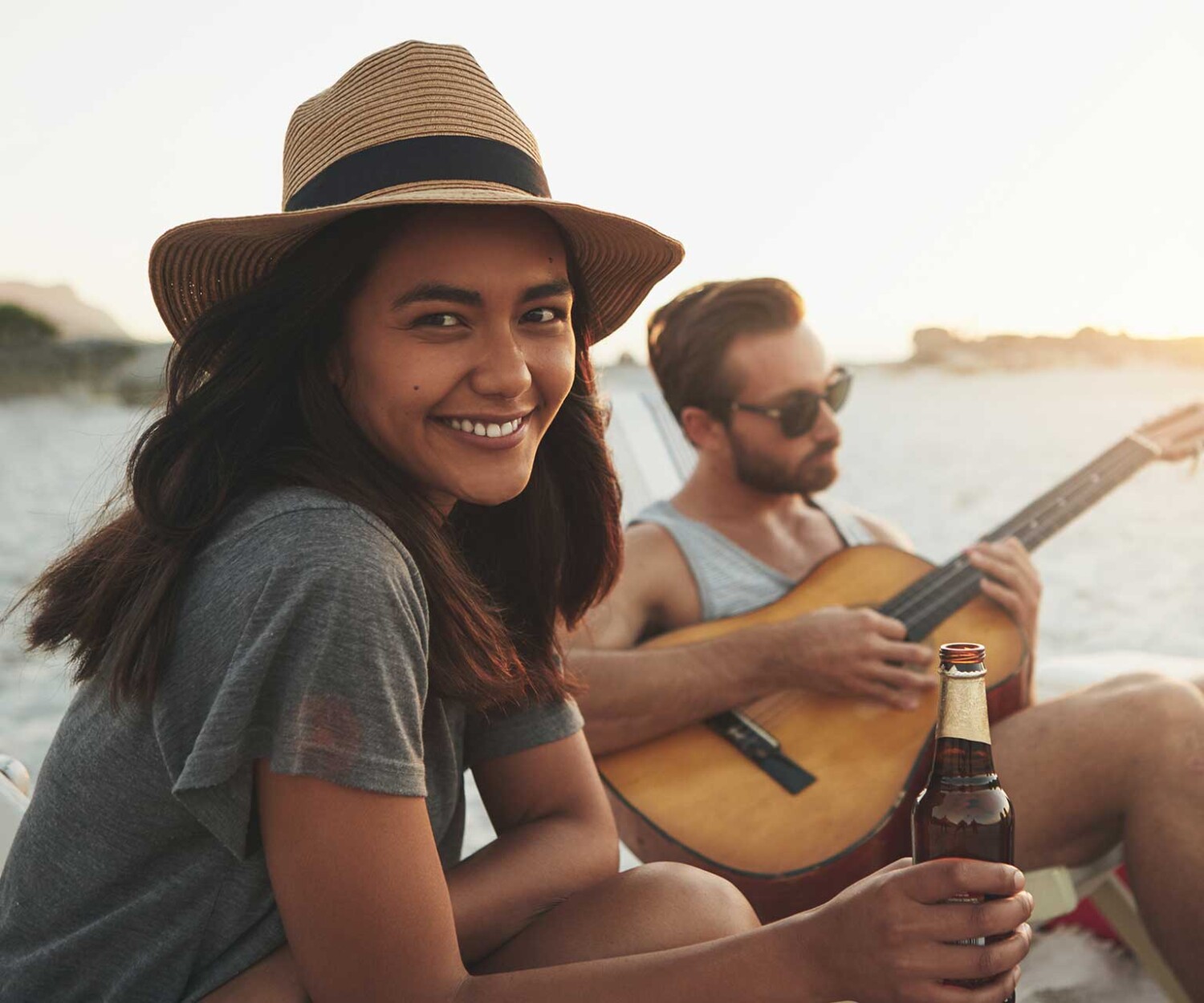 Friends spending time together at the beach with a guitar and a drinks