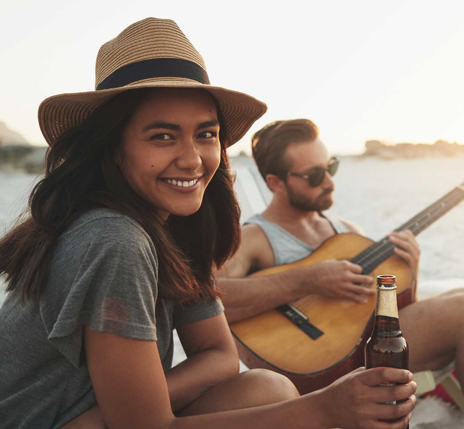 Friends spending time together at the beach with a guitar and a drinks