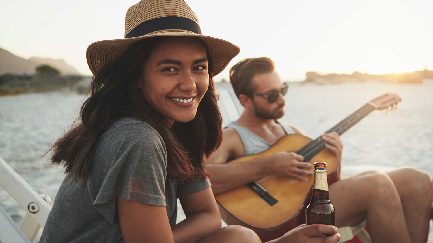 Friends spending time together at the beach with a guitar and a drinks