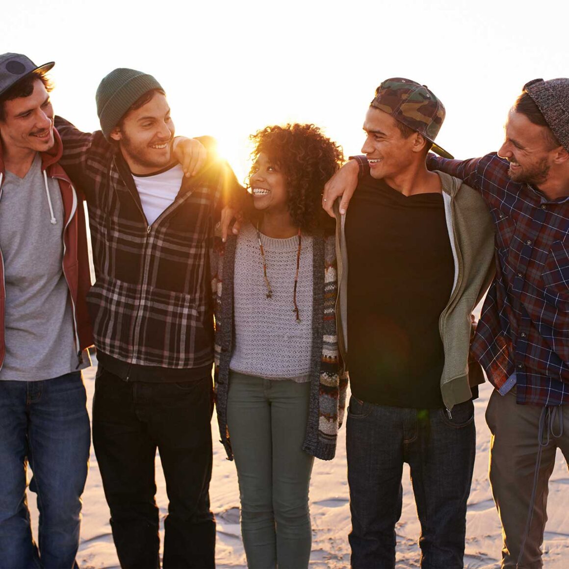 A group of friends walking along a beach at sunset
