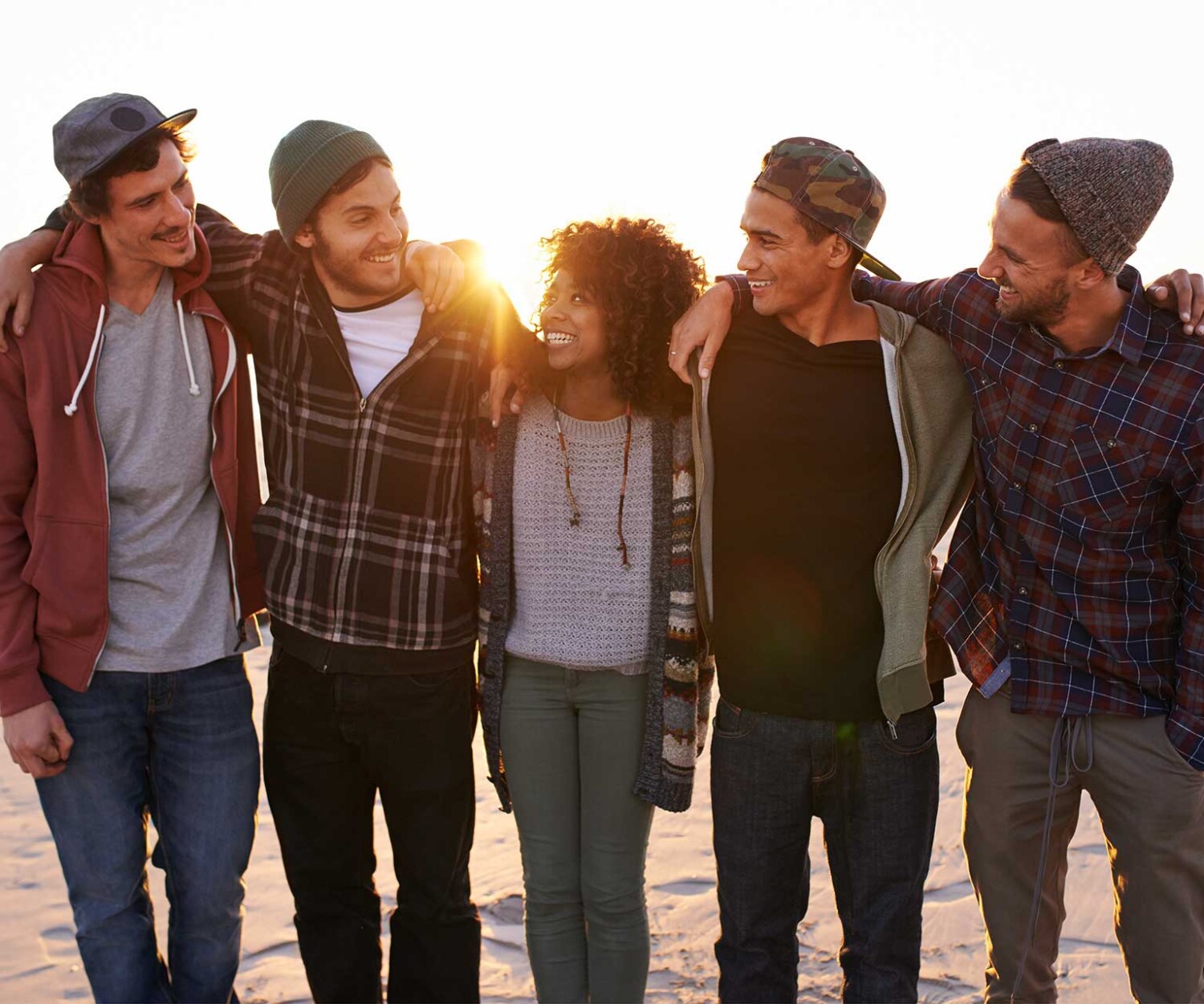 A group of friends walking along a beach at sunset