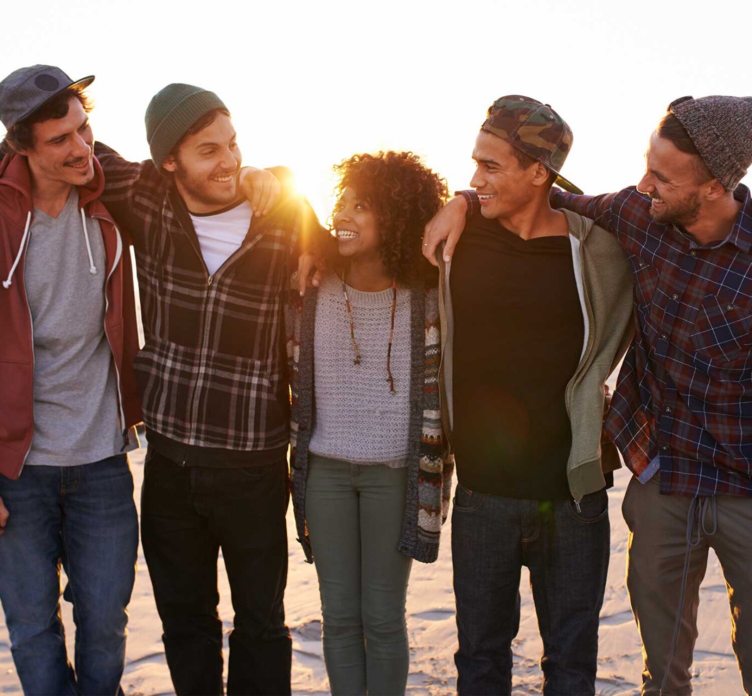 A group of friends walking along a beach at sunset