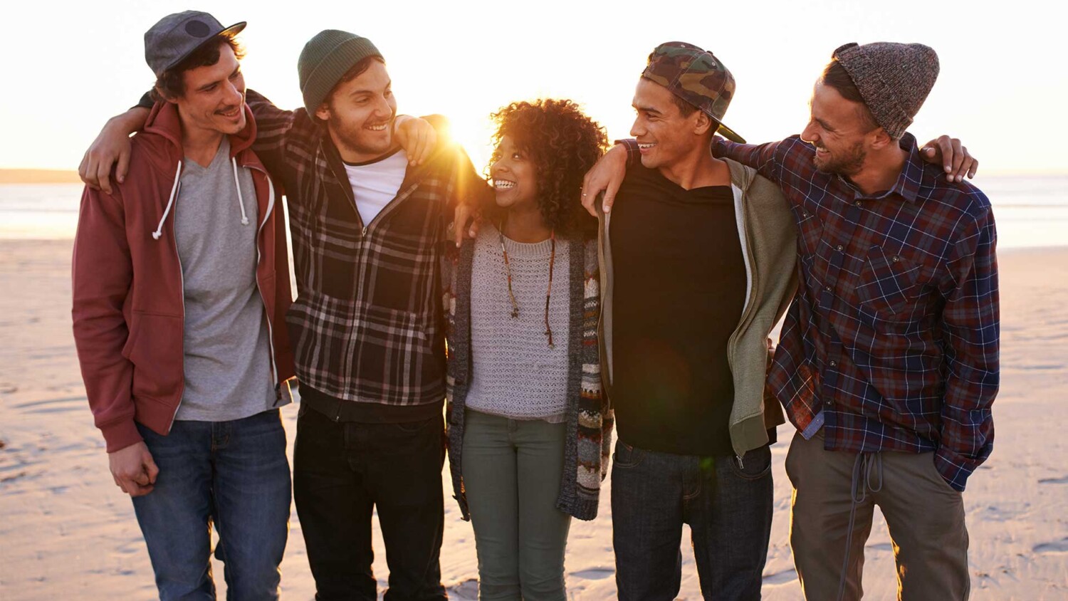 A group of friends walking along a beach at sunset